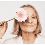 belle femme senior ménopausée heureuse et en bonne santé se cachant derrière fleur
