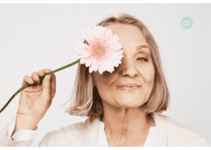 belle femme senior ménopausée heureuse et en bonne santé se cachant derrière fleur