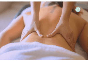 une femme dos nu est allongée sur une table de massage et des mains lui massent le dos