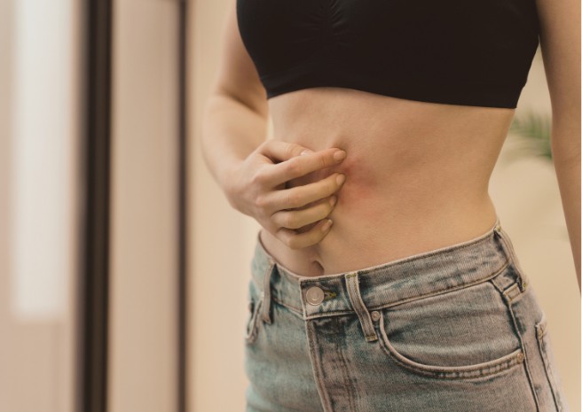 une femme se tient le ventre et semble gênée digestivement.