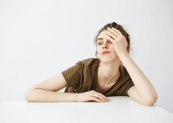 photo d'une jeune femme affalée su une table, visiblement épuisée ou s'ennuyant
