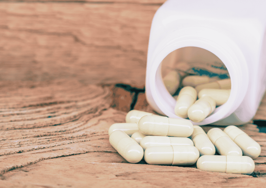 Flacon de gélules sur une table en bois, pour illustrer un traitement médical