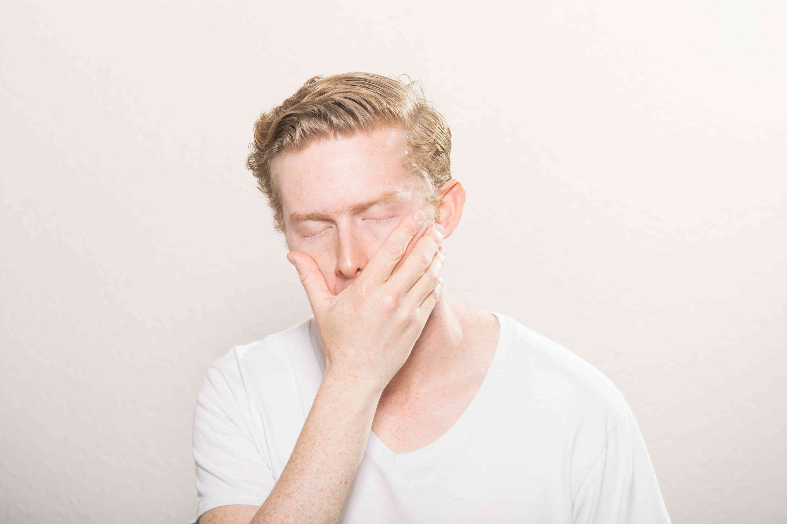 photo d'un homme qui ferme les yeux, met sa main devant la bouche et semble souffrir