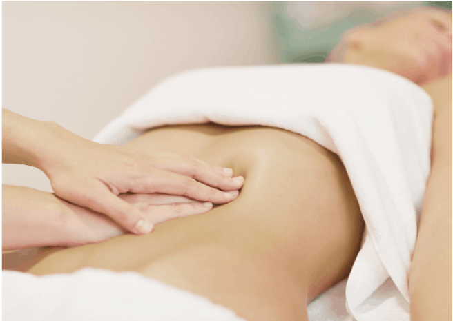 mains qui massent l'abdomen féminin. Le thérapeute exerce une pression sur le ventre.