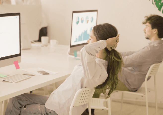 Photo d'une employée adoptant une position de détente au bureau face à son ordinateur, tenant les mains derrière la tête