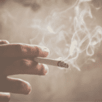 gros plan sur une main tenant une cigarette fumante