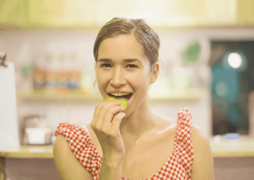 une femme heureuse en robe vichy mange une chips