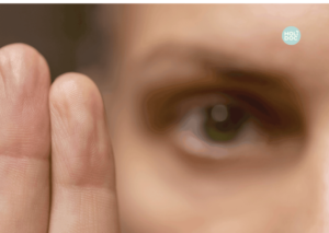 un oeil en fond nous fixe, 2 doigts au premier plan attirent notre attention